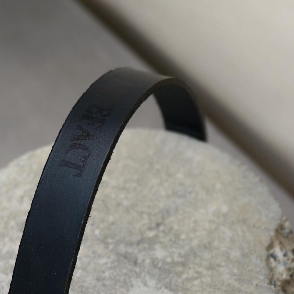Detail of black leather strap which has 'Artefact' stamped on it