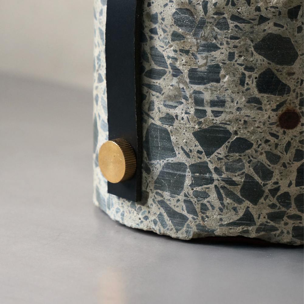 Detail of brass bolt holding in the leather strap. The bolt is drilled into the side of the concrete doorstop