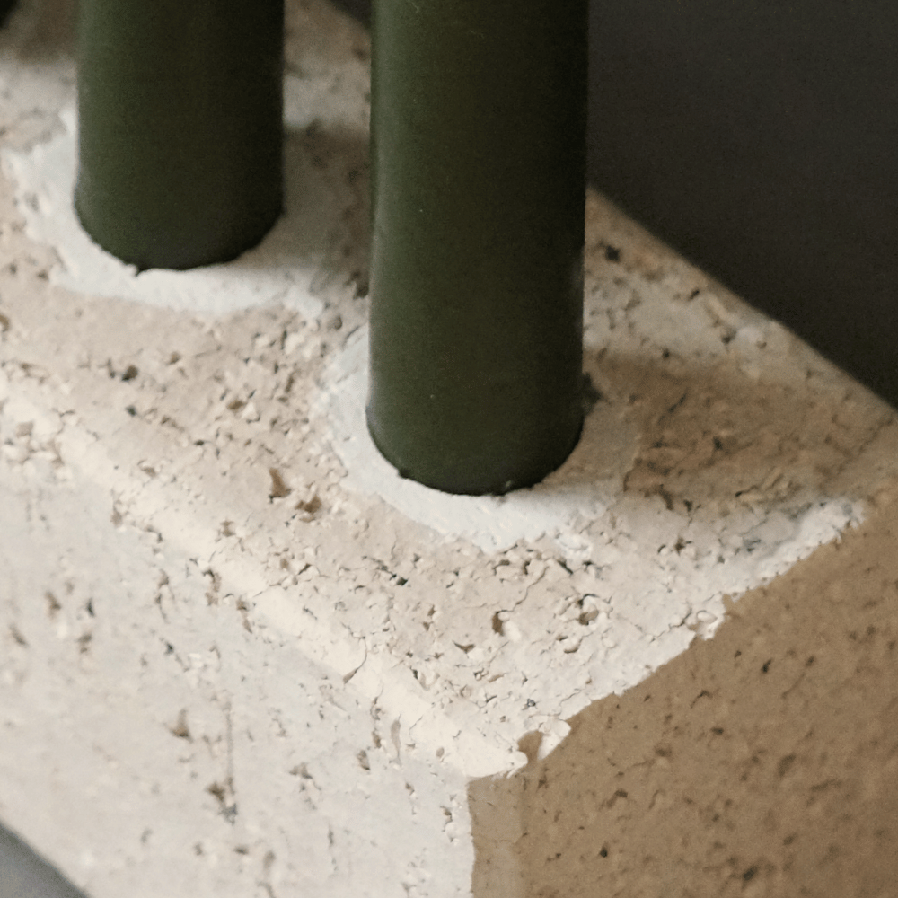 Close up view of the candle housing. Candles slot into grooves made from plaster. The plaster fills the hole in the brick, creating a slight white contrast against the sand coloured brick. Olive candles are in the grooves.